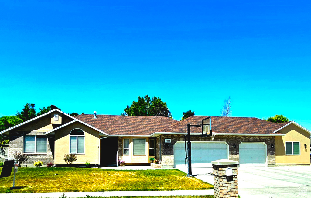 Ranch-style house featuring a garage, driveway, stucco siding, and a front yard