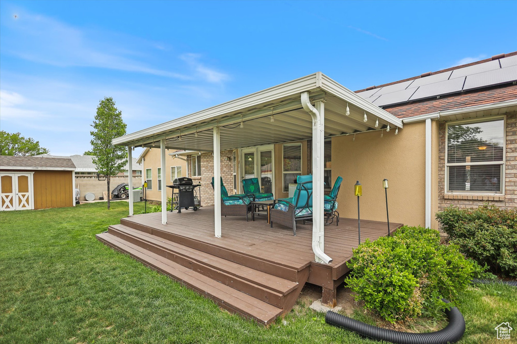 Wooden terrace with a lawn, a storage unit, an outdoor structure, area for grilling, and an outdoor living space
