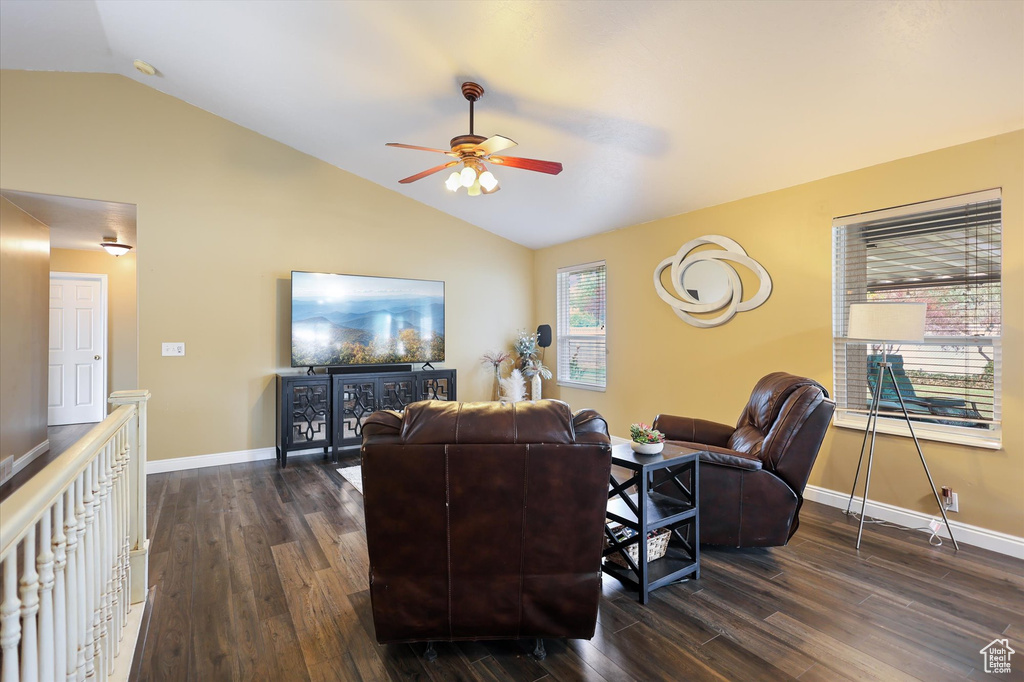 Living room with ceiling fan, vaulted ceiling, dark wood-type flooring, and baseboards