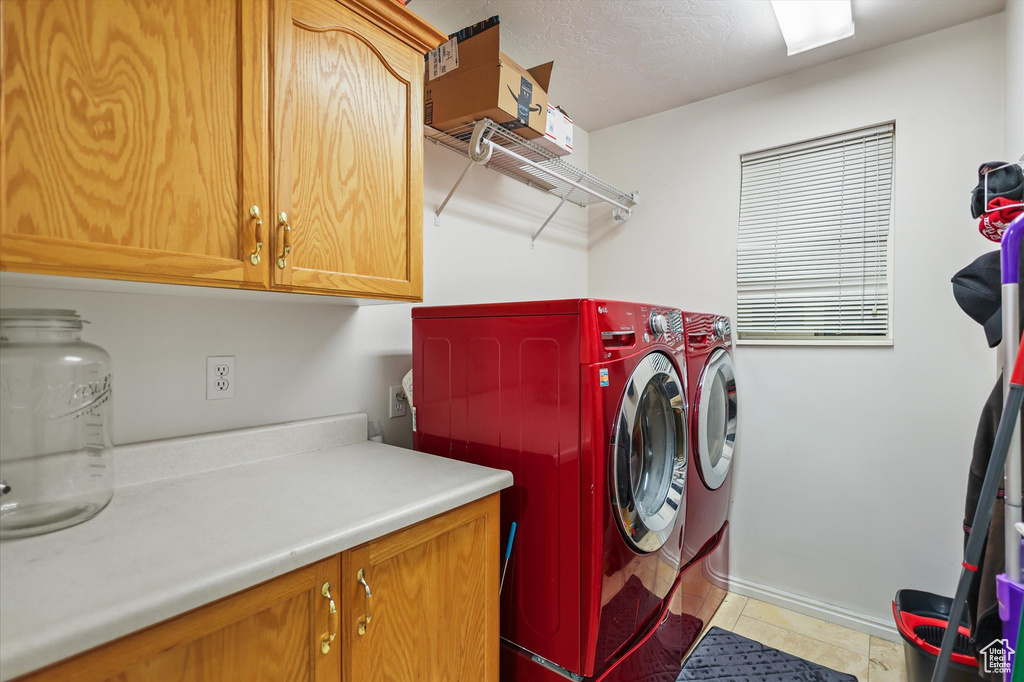 Laundry room featuring cabinet space, independent washer and dryer, baseboards, and light tile patterned floors
