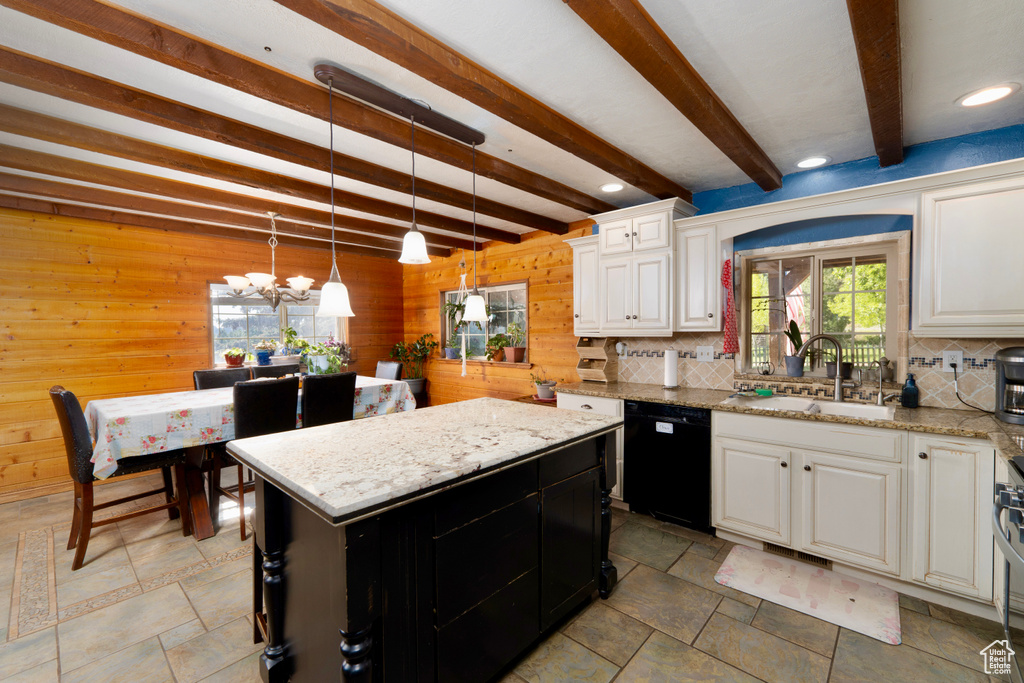 Kitchen with black dishwasher, a sink, wood walls, tasteful backsplash, and a chandelier