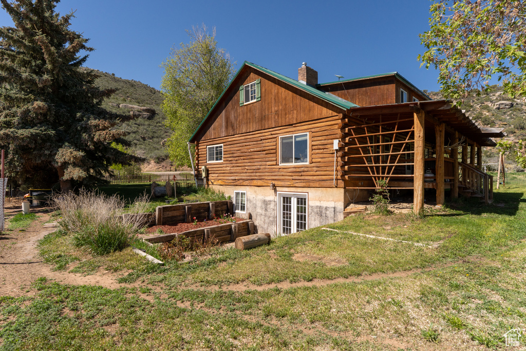 Rear view of property featuring log exterior, a yard, a chimney, a vegetable garden, and a deck