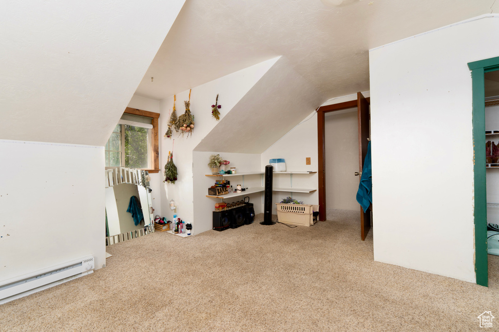 Additional living space with a baseboard radiator, carpet floors, and lofted ceiling