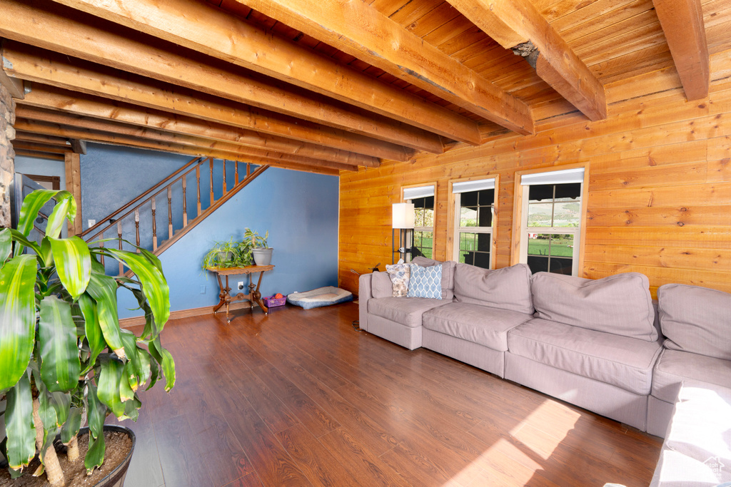 Living room featuring wooden walls, beamed ceiling, wood finished floors, stairway, and wood ceiling