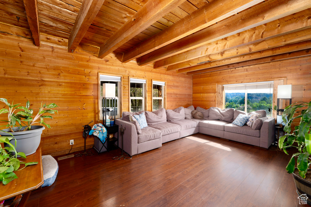 Living room featuring beam ceiling, wooden walls, wood-type flooring, and wood ceiling