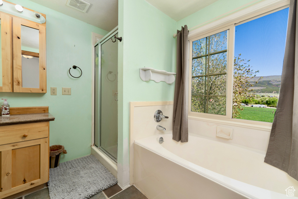 Bathroom featuring a stall shower, vanity, and a garden tub