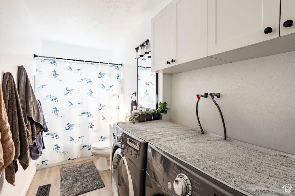 Laundry room featuring washing machine and clothes dryer and light wood-style floors
