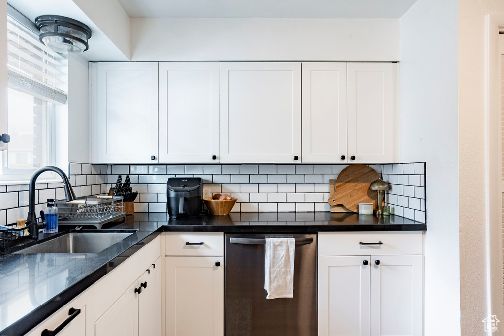 Kitchen with stainless steel dishwasher, a sink, and white cabinets
