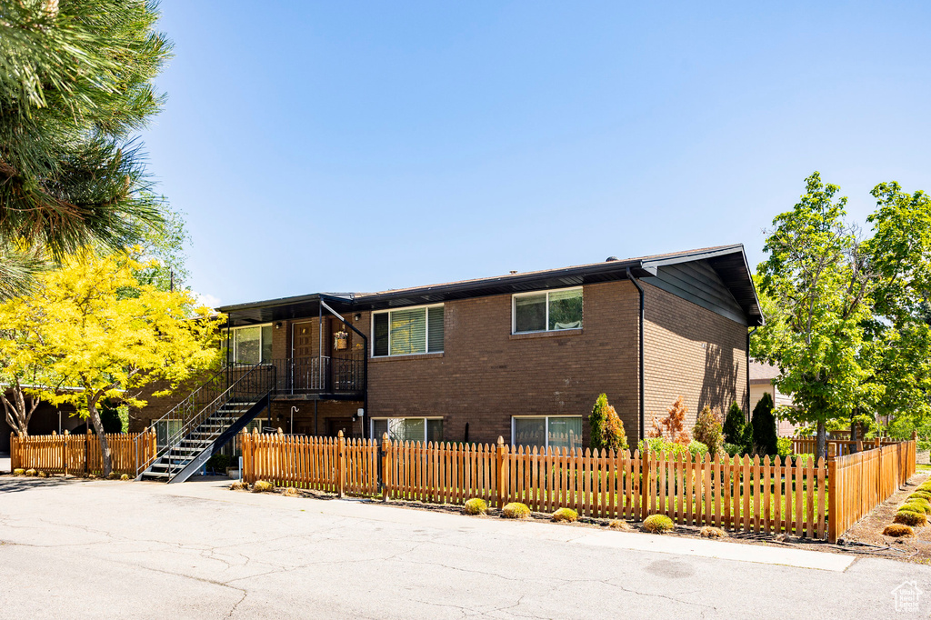 View of front of property with brick siding, a fenced front yard, and stairs