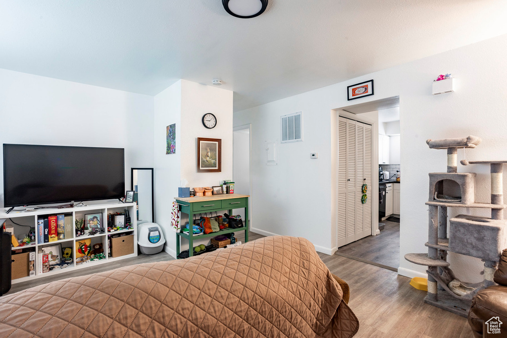 Bedroom with wood finished floors, a closet, and baseboards