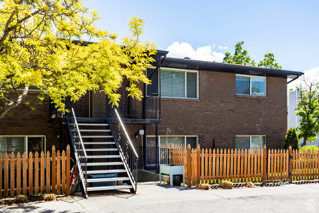 Back of house with stairway, a fenced front yard, and brick siding