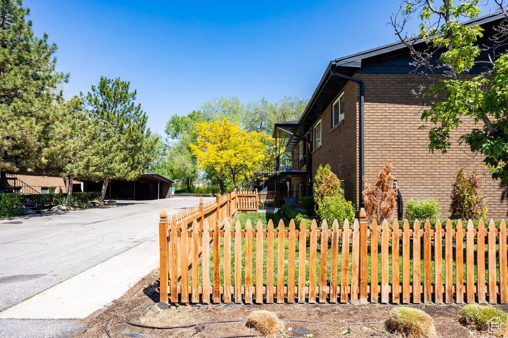 View of side of home featuring brick siding and fence