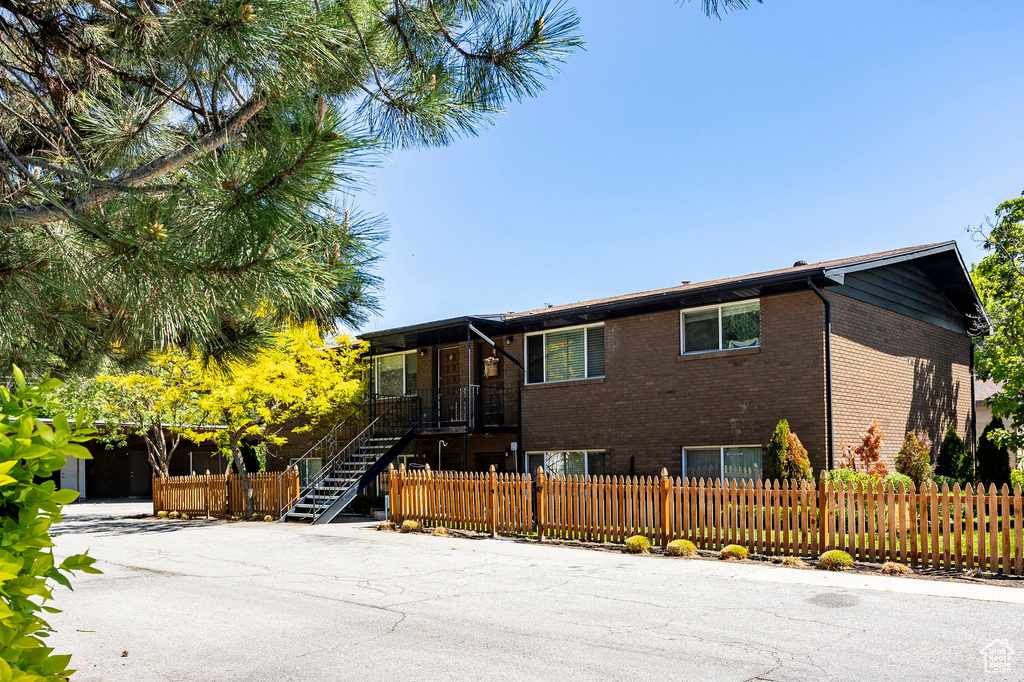Ranch-style home with brick siding, a fenced front yard, and stairs