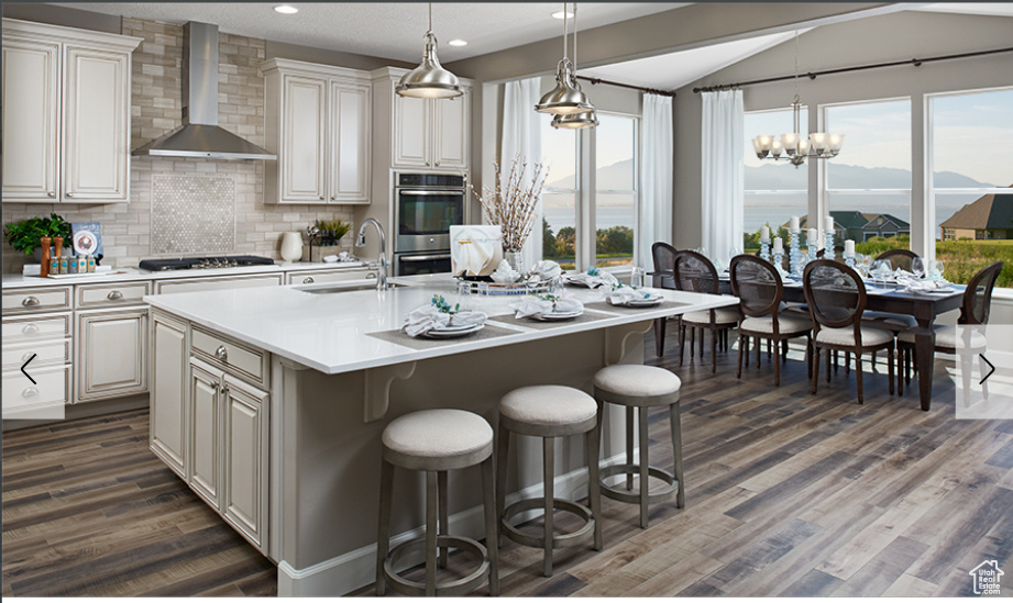 Kitchen featuring wall chimney range hood, a sink, light countertops, gas cooktop, and backsplash