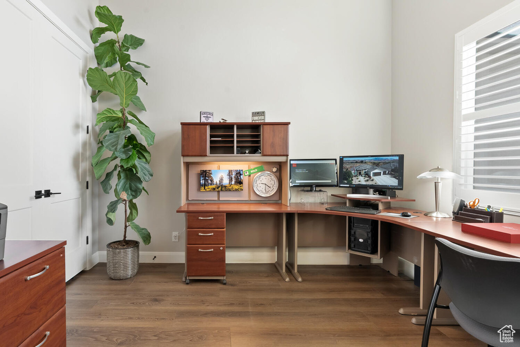 Office with wood finished floors and healthy amount of natural light