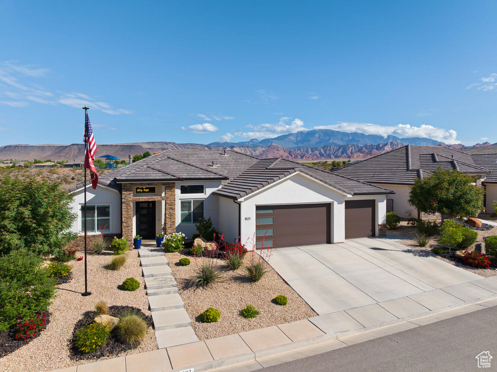 View of front facade with a garage, stucco siding, a mountain view, and driveway