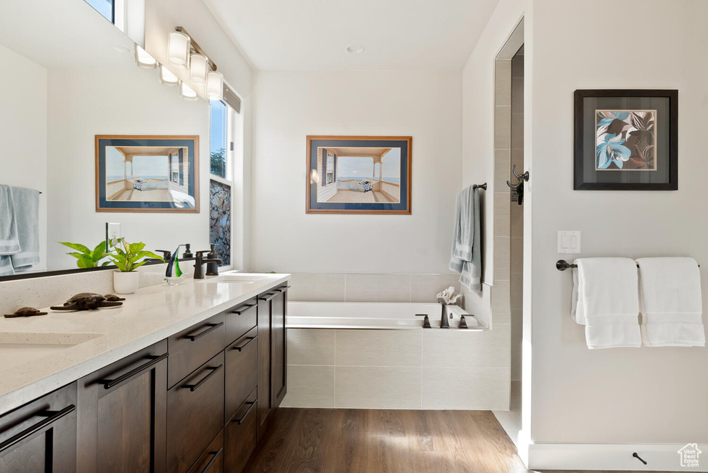 Full bath with wood finished floors, a garden tub, double vanity, and a shower