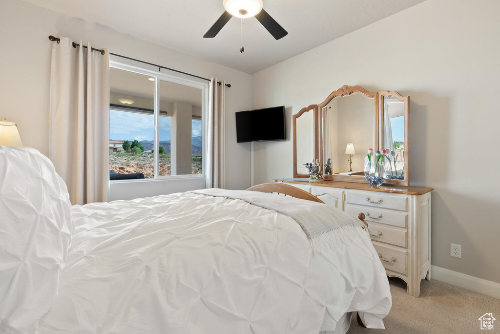 Bedroom featuring light carpet, baseboards, and a ceiling fan
