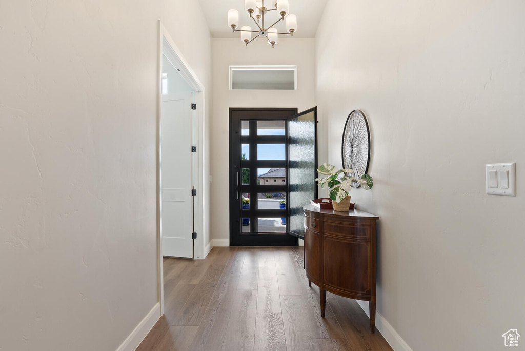 Entrance foyer with baseboards, a chandelier, and wood finished floors