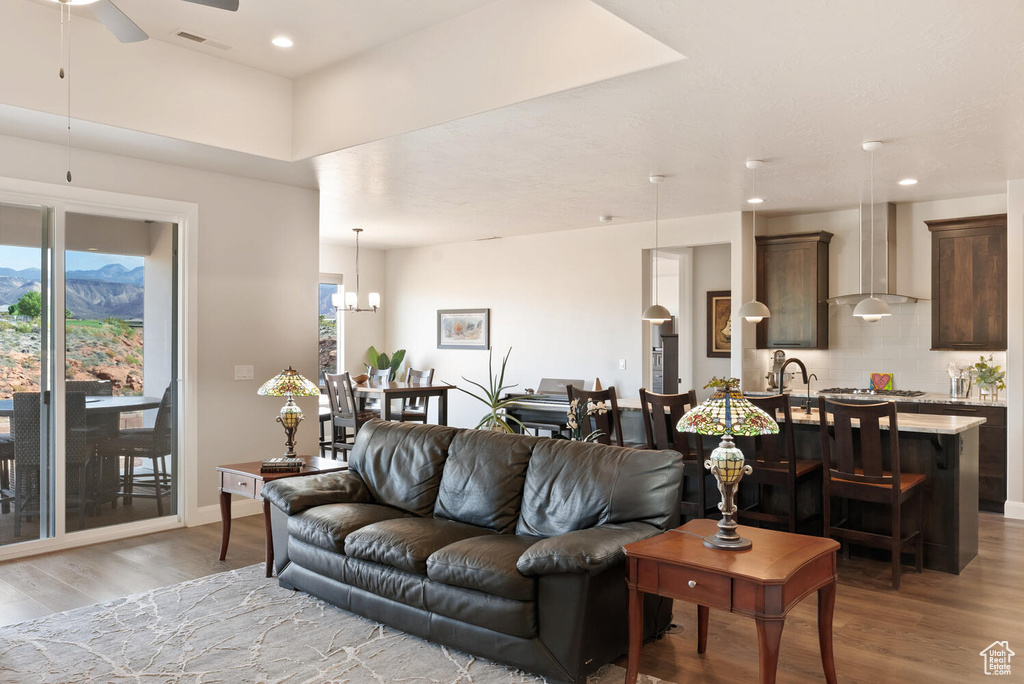 Living room with light wood finished floors, ceiling fan, a chandelier, recessed lighting, and baseboards