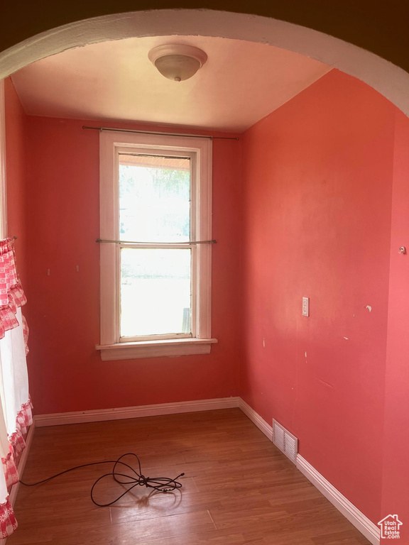 Spare room with arched walkways and light wood-type flooring