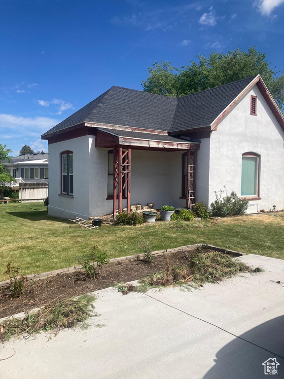View of front of property featuring roof with shingles, stucco siding, and a front yard