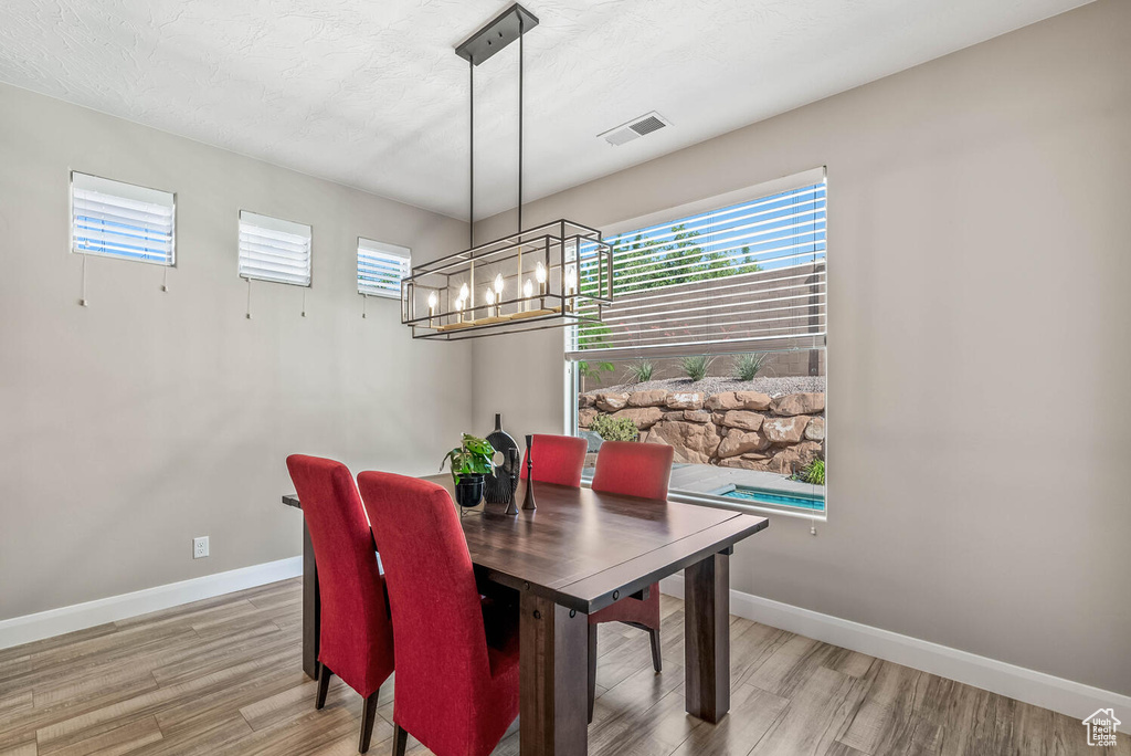 Dining area with a chandelier, healthy amount of natural light, light wood-style floors, and baseboards