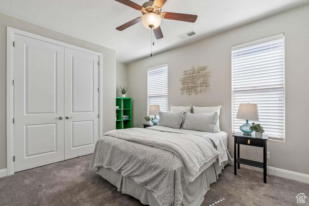 Carpeted bedroom with a closet, baseboards, and ceiling fan