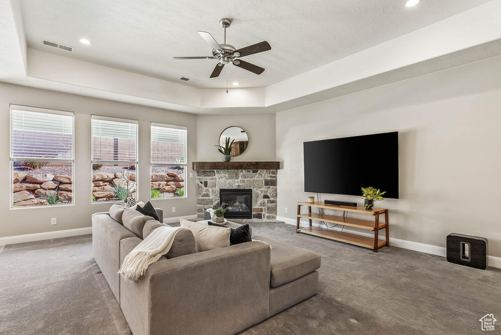 Living room with carpet, baseboards, ceiling fan, a fireplace, and recessed lighting