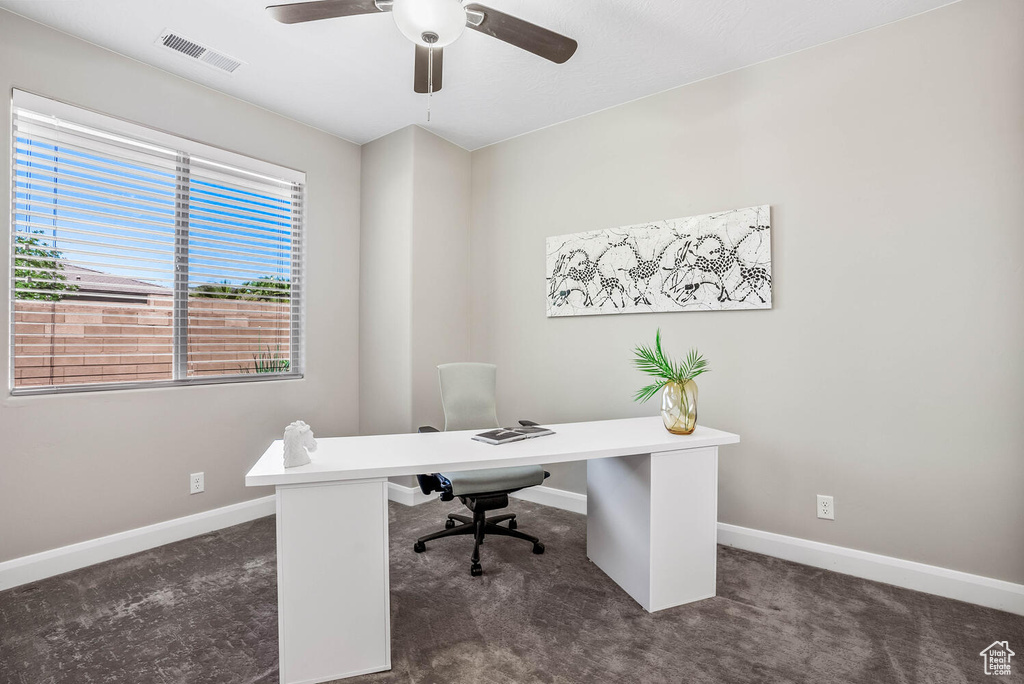 Home office featuring dark carpet, baseboards, and a ceiling fan
