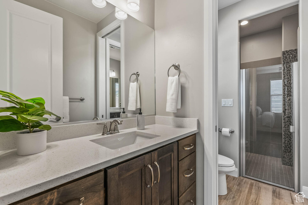 Bathroom with a shower stall, toilet, vanity, and wood finished floors