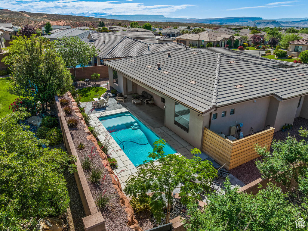 Rear view of house featuring a tiled roof, stucco siding, a patio, a fenced backyard, and a residential view