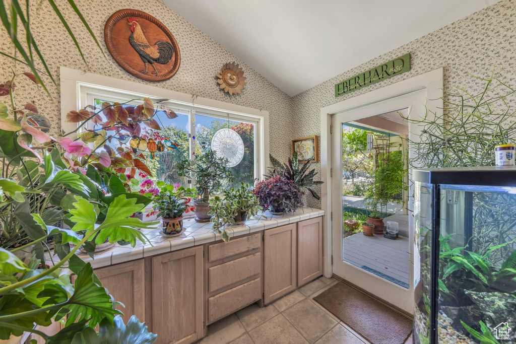 Doorway with wallpapered walls, vaulted ceiling, and healthy amount of natural light