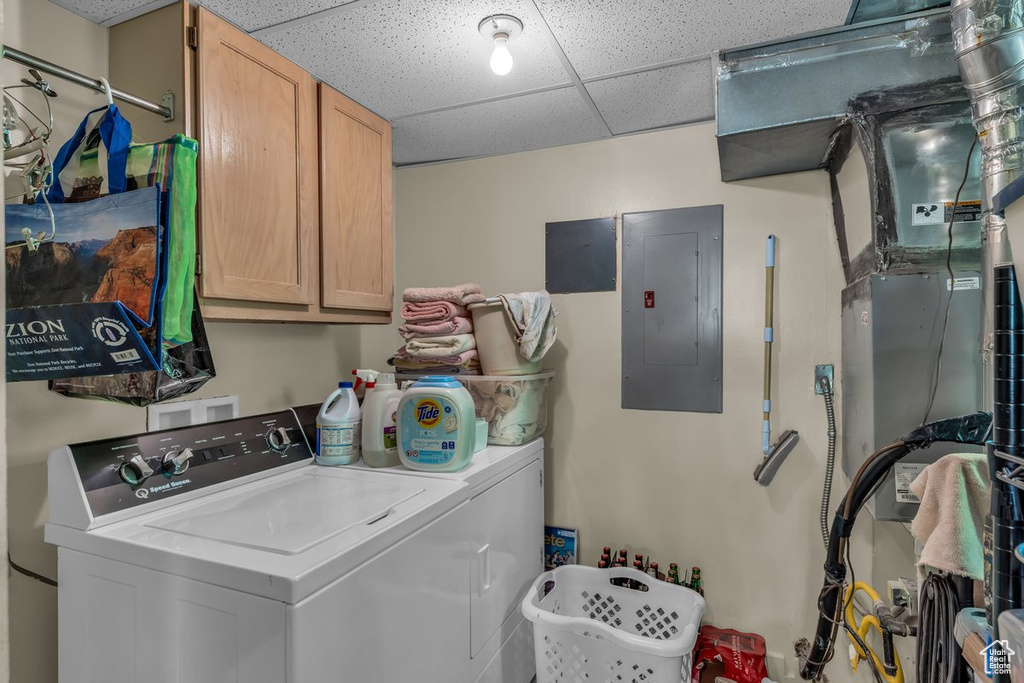 Clothes washing area featuring electric panel, washer and clothes dryer, and cabinet space