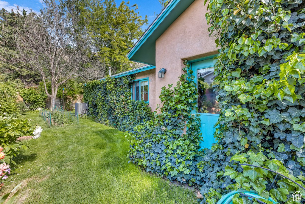 View of side of home with stucco siding and a yard