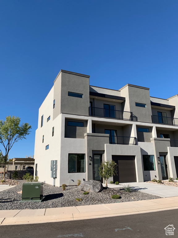 Modern home featuring stucco siding, an attached garage, and concrete driveway