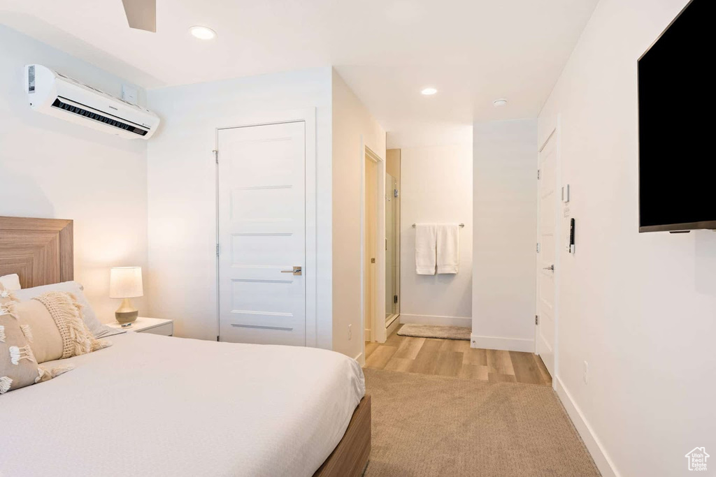 Bedroom with an AC wall unit, recessed lighting, light carpet, and baseboards