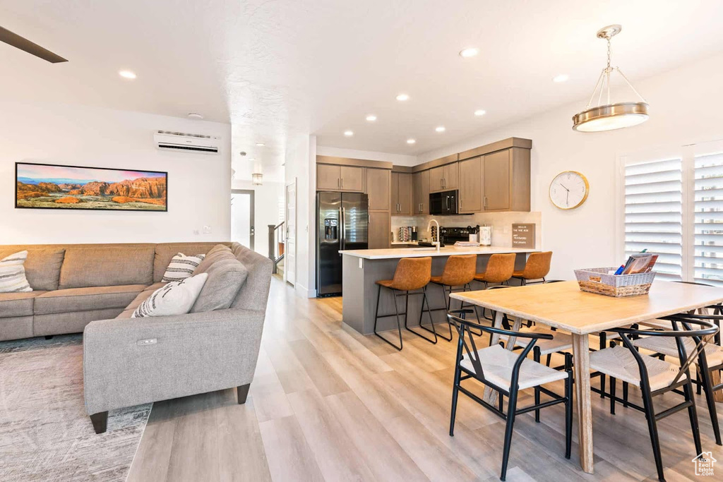Dining area with a wall unit AC, light wood finished floors, and recessed lighting