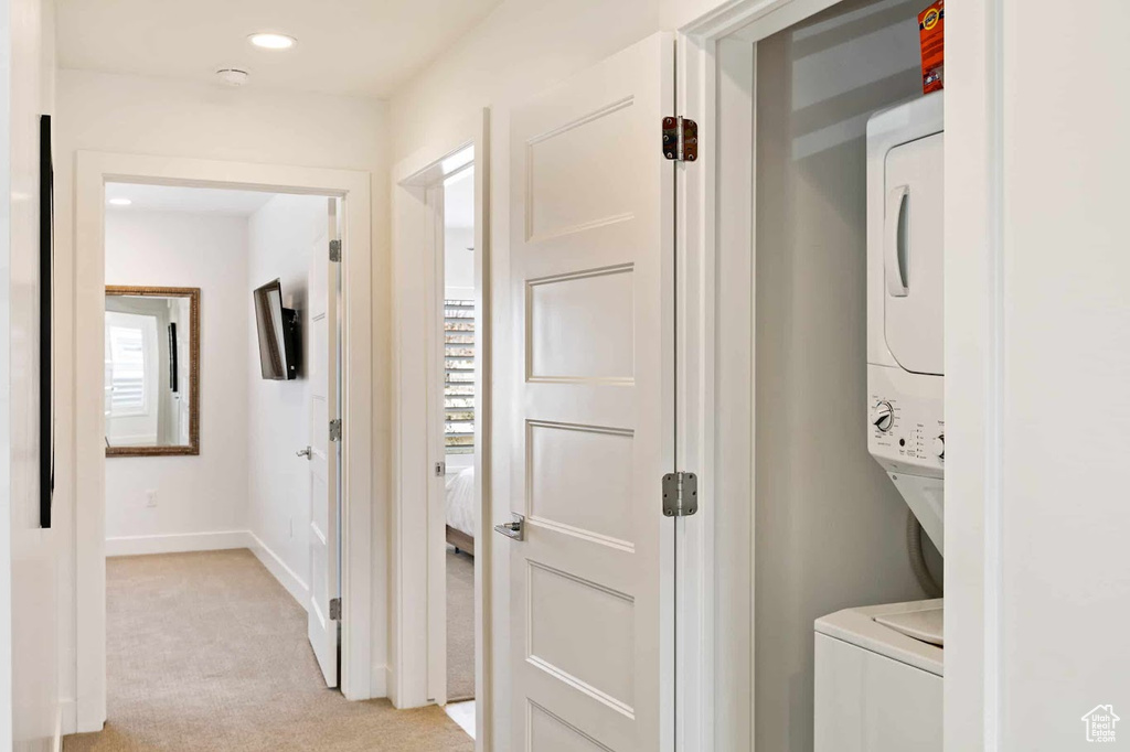 Hall with estacked washer and dryer, light colored carpet, recessed lighting, and baseboards