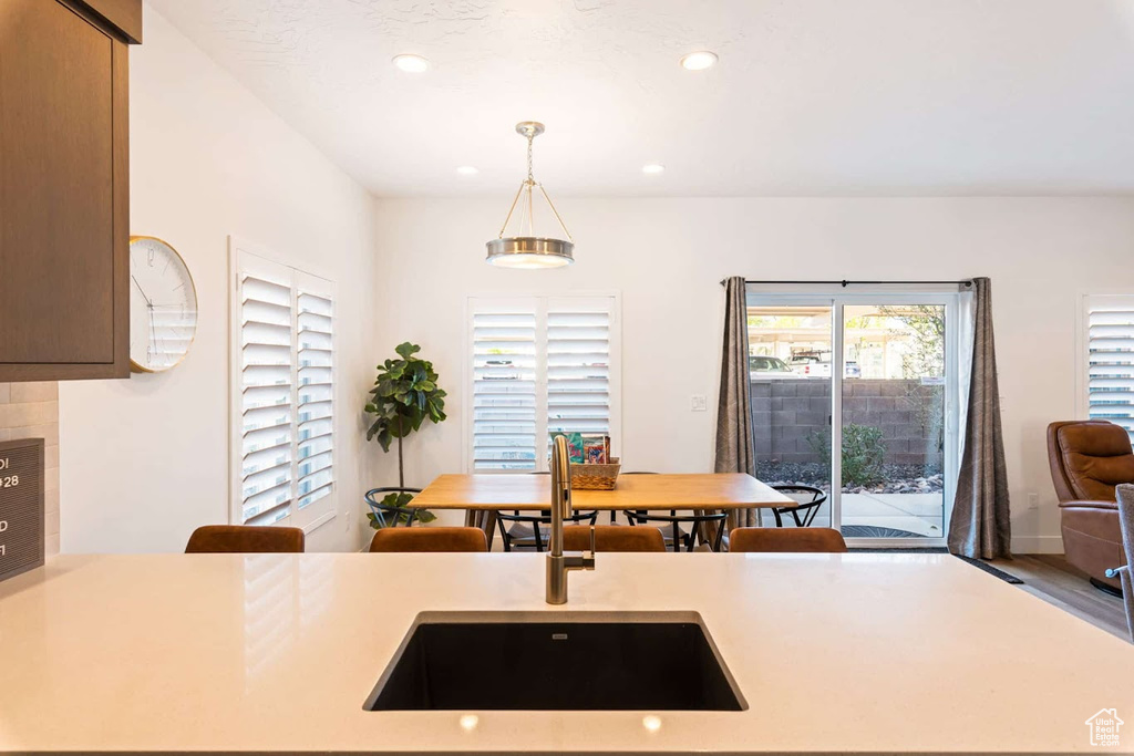Kitchen with a sink, light countertops, hanging light fixtures, and recessed lighting