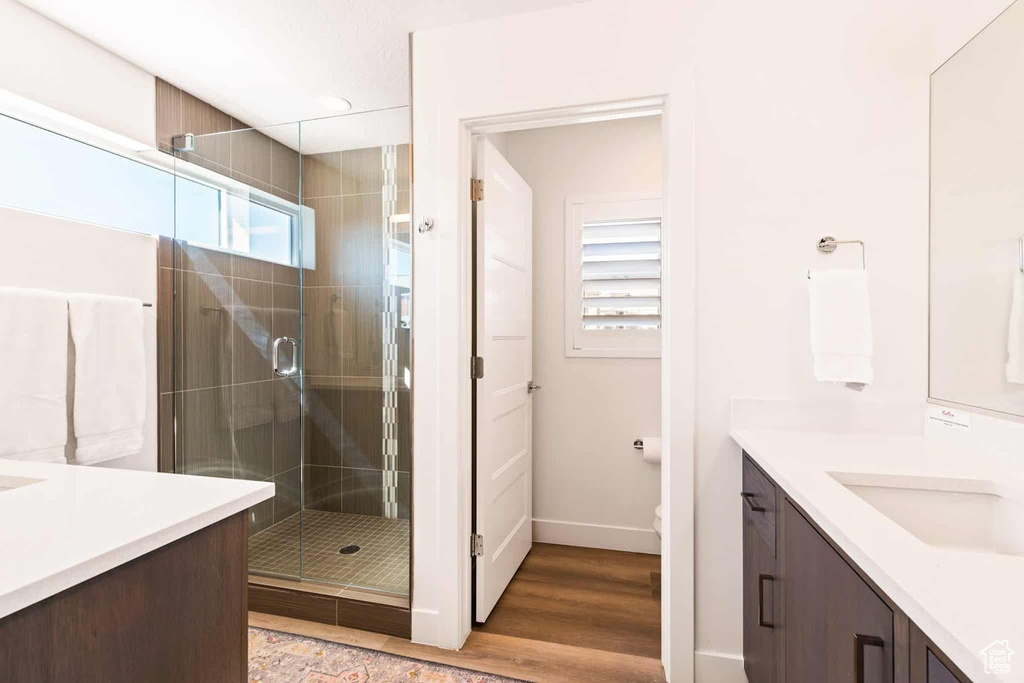 Bathroom featuring a stall shower, vanity, baseboards, and wood finished floors