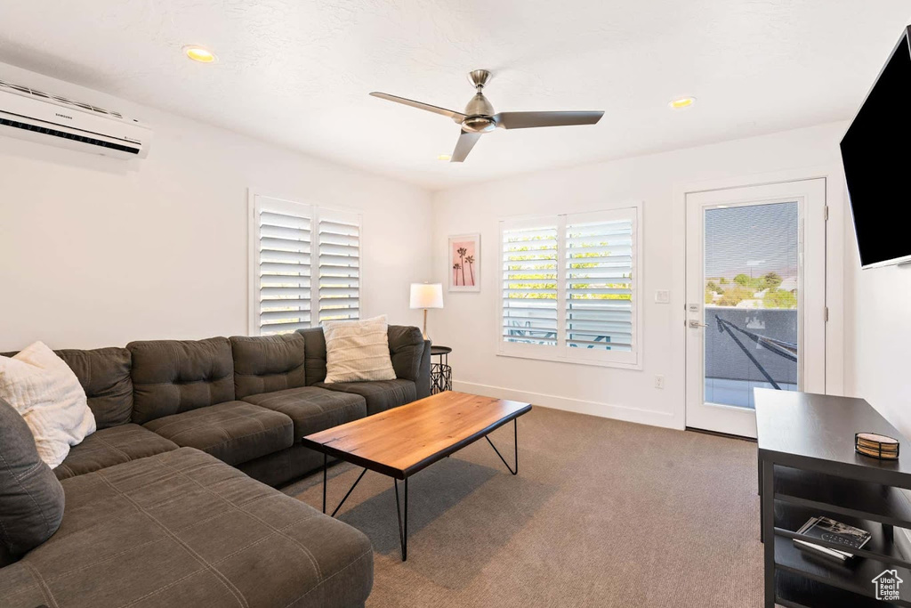 Carpeted living room featuring an AC wall unit, a ceiling fan, baseboards, and recessed lighting