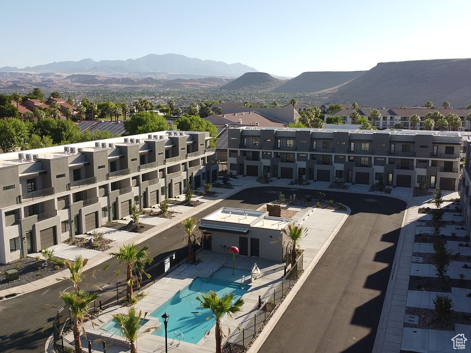 Drone / aerial view of a pool, mountains, and apartment complex / building