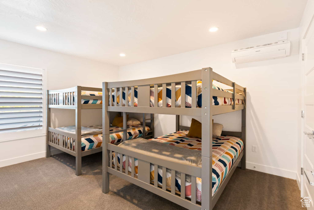 Carpeted bedroom featuring a wall mounted air conditioner, baseboards, and recessed lighting