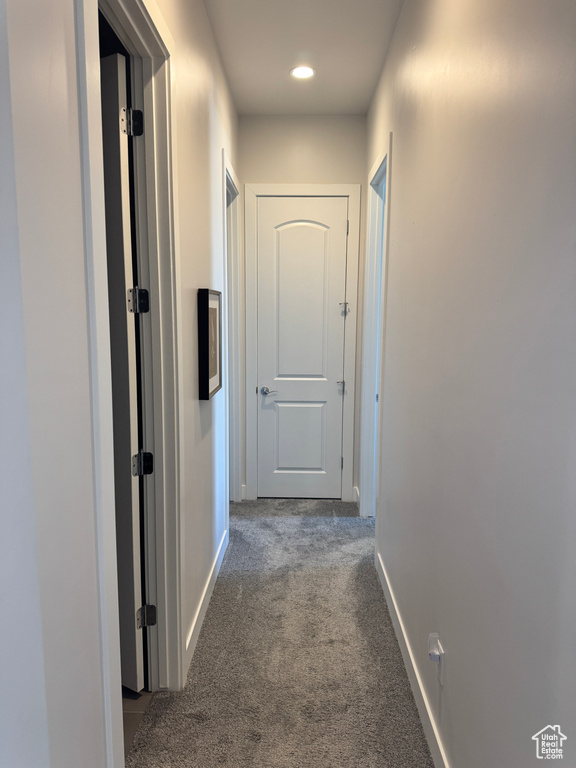 Hall with dark colored carpet, baseboards, and recessed lighting