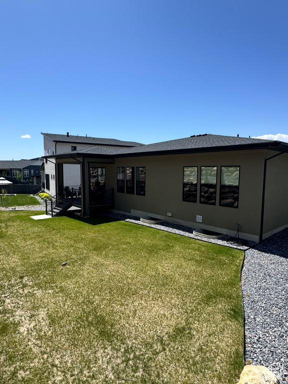 Back of property featuring a yard and a shingled roof