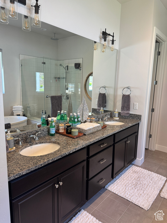 Full bath with a stall shower, double vanity, tile patterned floors, and baseboards