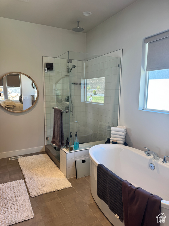 Bathroom featuring a stall shower, a soaking tub, tile patterned flooring, and baseboards