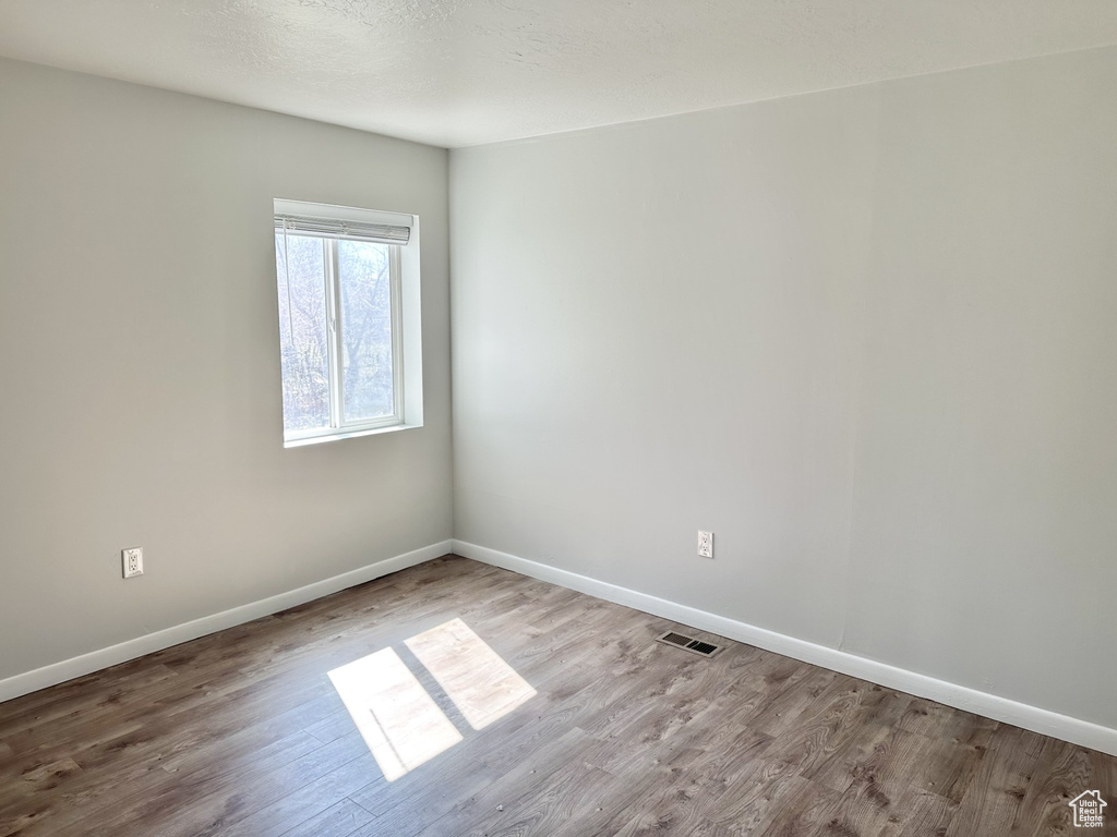Empty room featuring wood finished floors, baseboards, and visible vents