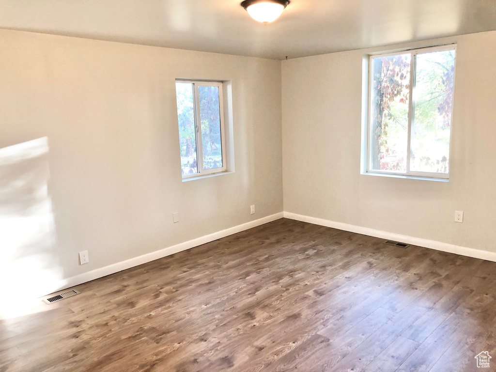 Spare room featuring visible vents, dark wood-style flooring, and baseboards